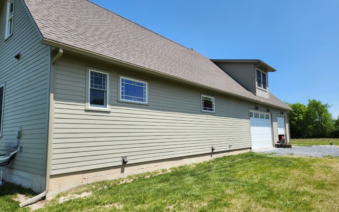 Sage green barn-style garage in Addison County VT with white seamless gutters