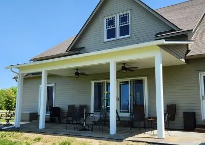 Sage green Vermont home with a covered patio and white seamless gutters above
