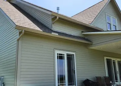 Sage green Vermont home with seamless gutters across multiple roof lines