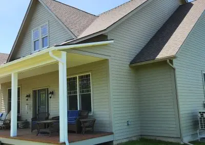 Vermont home with a covered porch, wicker furniture, and white seamless gutters