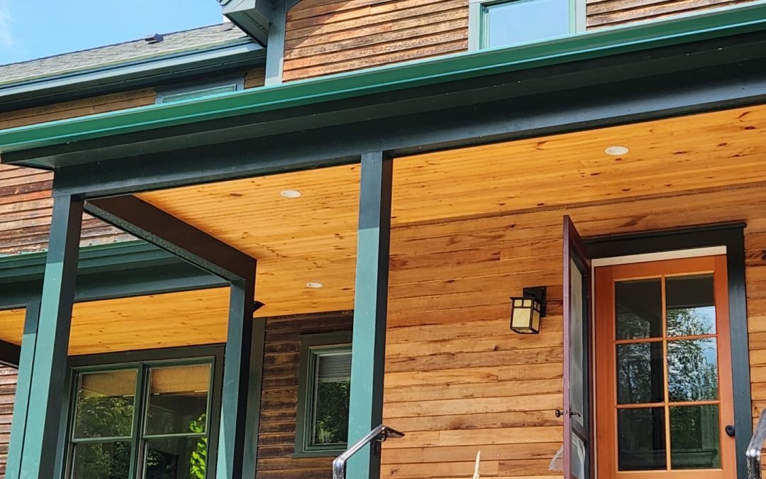 Green seamless gutters on a cedar-sided Vermont home with a covered porch