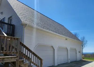 White three-bay garage in Addison County VT with seamless gutters and a mountain view