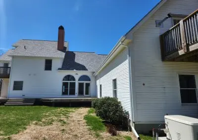 Rear of a white colonial Vermont home with white seamless gutters and downspouts