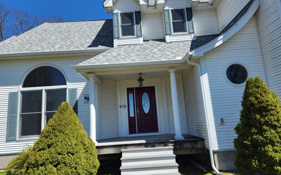 White cape home in Chittenden County VT with seamless gutters above a columned entry
