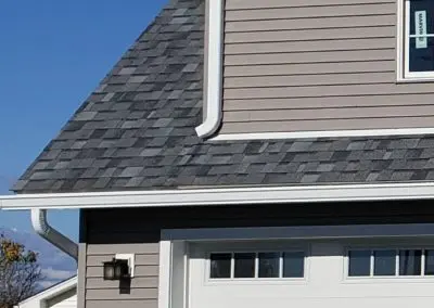 Taupe garage in Addison County VT with a white seamless gutter and downspout