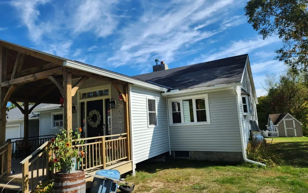White farmhouse in Addison County VT with a timber-frame porch and seamless gutters